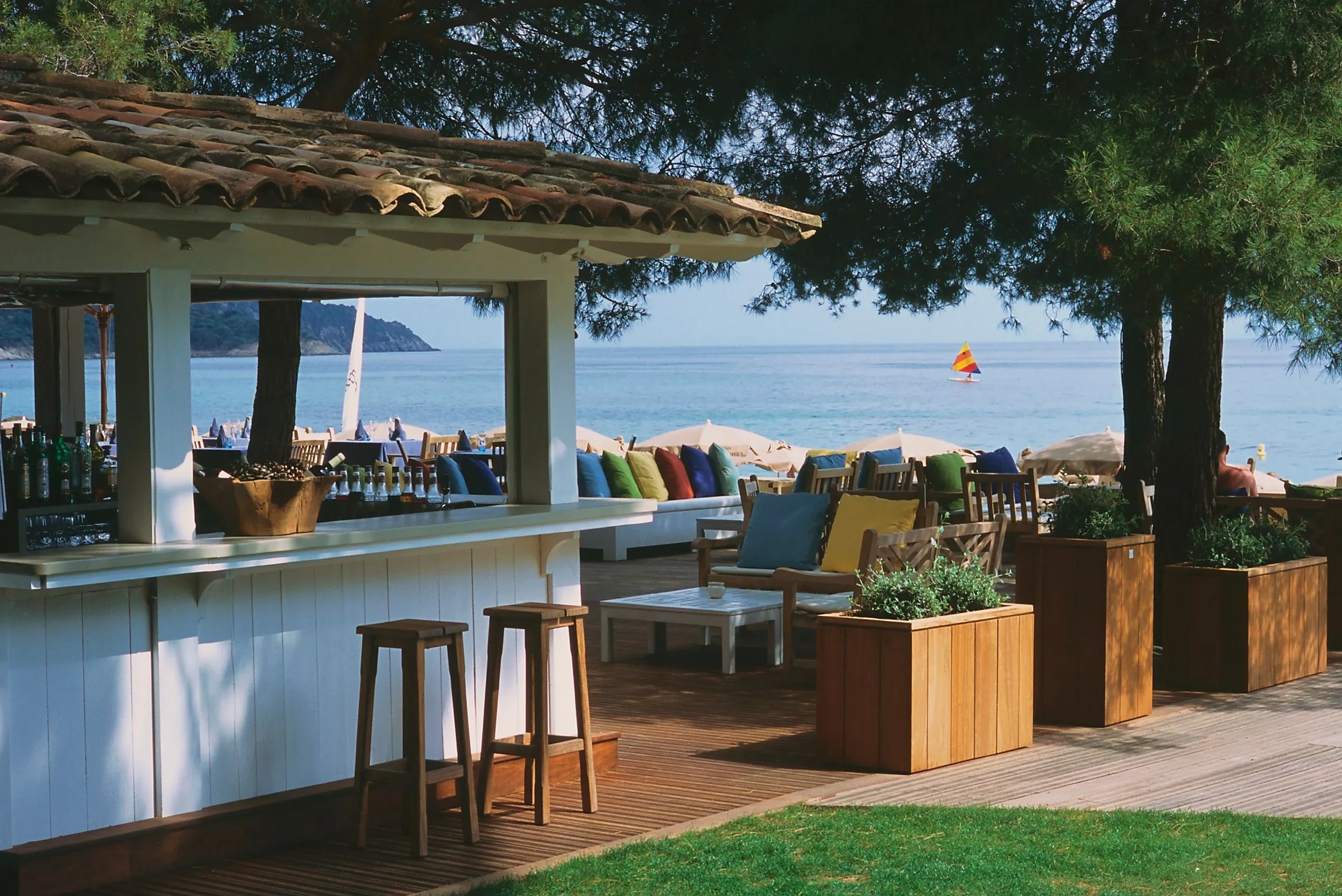 Bar en bord de mer, chaises et parasols colorés.